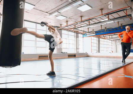 Professionelle erfahrene Trainer Controlling die Ausbildung des Jungen, volle Länge Foto Stockfoto