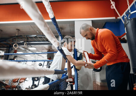 Trainer helfen, junge für Boxing vorzubereiten. close up Side View Photo. Lifestyle, Hobby, Interesse Stockfoto