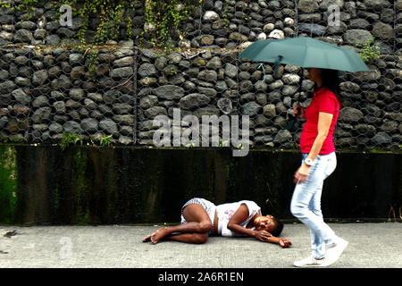 ANTIPOLO CITY, Philippinen - Oktober 11, 2019: Fußgänger Wanderungen vorbei an schlafenden Obdachlosen auf der Straße. Stockfoto