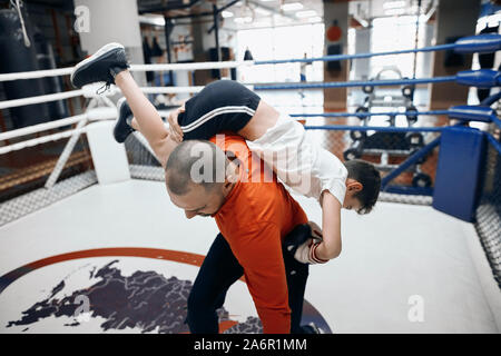 Young Professional Trainer zeigen, wie der Gegner zu kleinen Jungen in Angriff zu nehmen, ihn zu lehren, sich selbst zu schützen. nach oben schließen Foto Stockfoto