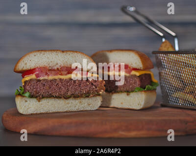 Vegan auf Basis pflanzlicher Burger in der Hälfte mit Pommes auf Holz Tablett serviert. Stockfoto