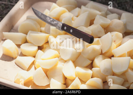 Rohe Kartoffeln in Scheiben und Messer auf einem Tablett legen Stockfoto