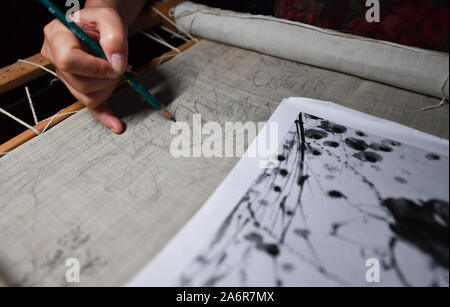 (191123) - NANCHANG, Oktober 28, 2019 (Xinhua) - Zhang Xiaohong zeichnet den Entwurf der Stickerei an Ihre Werkstatt in Xinyu City, East China's Jiangxi Province, Okt. 23, 2019. Zurück zu der Nördlichen Song Dynastie (960-1127), Xiabu, oder Gras Bettwäsche datiert, ist eine Art Tuch aus Ramie gemacht. Zhang Xiaohong, 61 Jahre alt, ist eine repräsentative nationale Erbe der Xiabu Stickerei. Im Jahr 2002 stellte sie eine Stickerei in ihrer Heimatstadt Xinyu nach dem Studium in Tianjin und Suzhou. Im Laufe der Jahre, Zhang die Qualität der Tuch aktualisiert und auch erstellt wurden sechs Möglichkeiten der Stiche. Im Jahr 2014 war sie erkennen Stockfoto