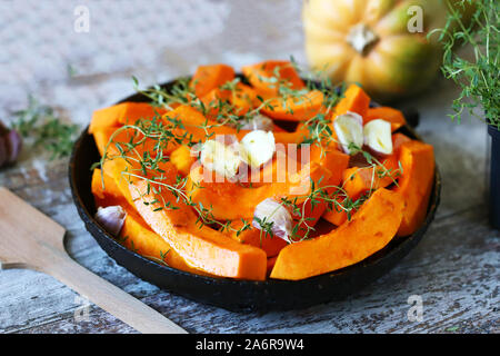 Kürbisscheiben mit Thymian und Knoblauch in einer Pfanne vor dem Backen. Gesunde Herbstkost. Veganes Mittagessen. Stockfoto