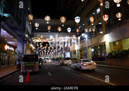 QUEZON CITY, Philippinen - 17. OKTOBER 2019: bunte Lichter über belebten Straße hängen mit Reihen von Restaurants im Central Business District von Que Stockfoto