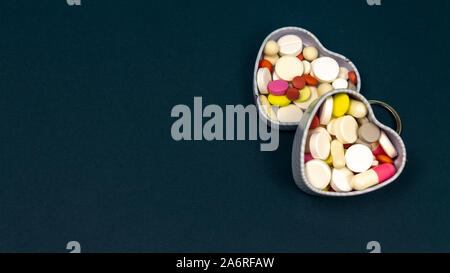 Eisen Herz box für Tabletten auf einem dunkelblauen Hintergrund. Rund, oval, weiß, rot. close-up Stockfoto