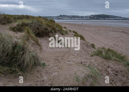 Menschen gehen auf instow Beach in Devon, England an einem bewölkten Tag. Es gibt Sand dune Sünde im Vordergrund. Stockfoto