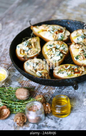 Halbierte Birnen in einer Pfanne gebacken mit Dorblu Käse, Honig, Nüssen und Thymian. Französische Küche. Keto Diät. Selektive konzentrieren. Stockfoto