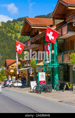 Lauterbrunnen, Schweiz - Oktober 10, 2019: Stadt street view in Alpine Village im Herbst, Holzhäuser mit Fahnen, Geschäfte in den Schweizer Alpen Stockfoto