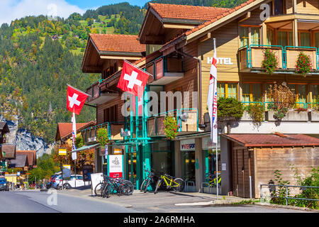 Lauterbrunnen, Schweiz - Oktober 10, 2019: Stadt street view in Alpine Village im Herbst, Holzhäuser mit Fahnen, Geschäfte in den Schweizer Alpen Stockfoto