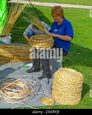 Eine Frau von Derbyshire Imker einen Strohhalm Bienenstock in Chatsworth Spiel oder Country Fair, Chatsworth House, Derbyshire, England, Großbritannien Stockfoto