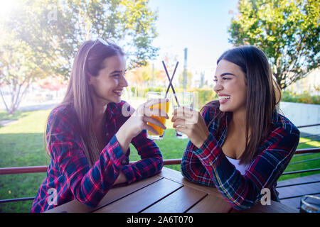 Zwei junge Frauen trinken Saft und Limonade in den Park an einem sonnigen Tag Stockfoto