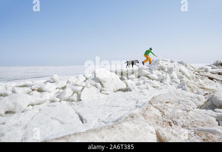 Junge erwachsene Mann draußen mit seinem Hund Spaß im Winter Landschaft Stockfoto