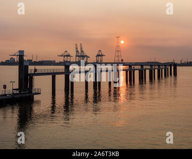 Pier in Schelde mit Container Terminal auf dem Hintergrund bei Sonnenuntergang, der Hafen von Antwerpen, Belgien. Stockfoto