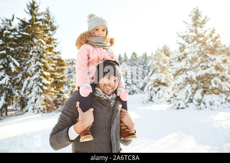 Vater mit seiner Tochter auf seinen Schultern im Winter im Park Stockfoto