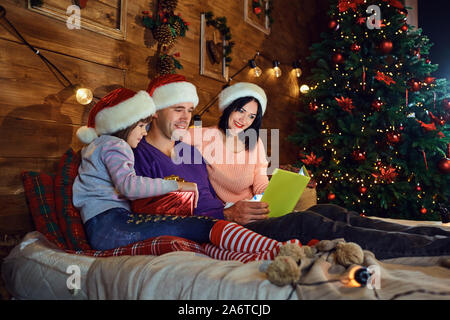 Familie ist das Lesen eines Buches in einem Zimmer in Weihnachten. Stockfoto