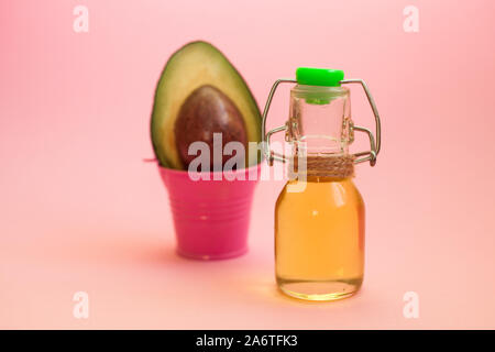 Avocado- und Avocado Öl in der Flasche auf rosa Hintergrund. Ansicht von oben. Kopieren Sie Platz. Beauty Produkt für Hautpflege, Wellness und medizinische Zwecke. Stockfoto