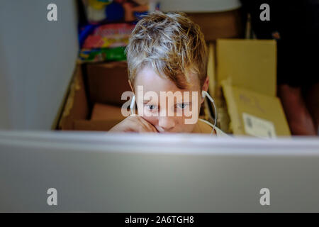 Ein kleiner Junge in Spielen, Computer Video Game, das auf einem Computer gefesselt. Stockfoto