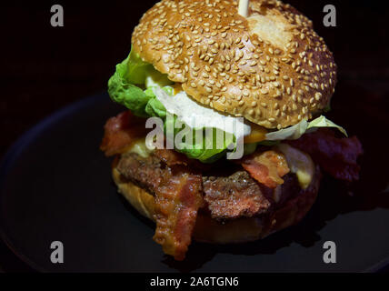 Amerikanische Küche Konzept. Eine saftige Burger mit Fleisch, Tomaten und Salat. Kochen Burger zu Hause. Hintergrundbild für ein Menü in Restaurants oder Cafes. Burg Stockfoto