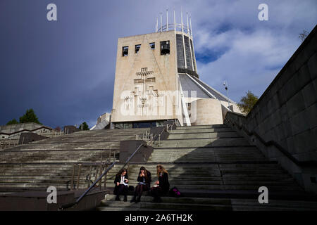 Drei Schülerinnen essen Ihr Mittagessen auf den Stufen der Kathedrale von Liverpool Stockfoto