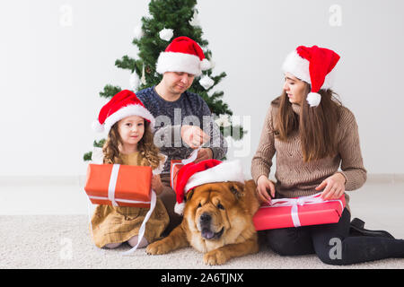 Pet, Urlaub und festliche Konzept - Familie mit Hund stehen in der Nähe der Weihnachtsbaum. Stockfoto