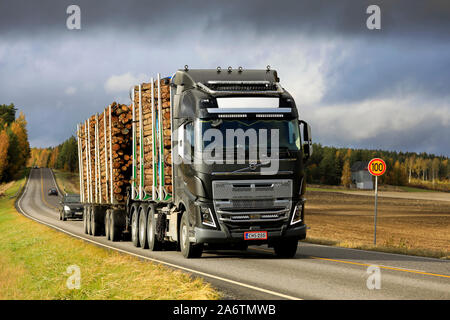 Schwarzer Volvo FH 16 750 Lkw zieht voll Holz Anhänger entlang der Autobahn 52 unter dramatischen herbstlichen Himmel angepasst. Salo, Finnland. Oktober 11, 2019. Stockfoto