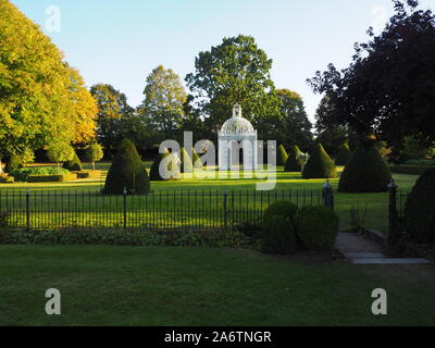 Das Parterre an chenies Manor Garden, Buckinghamshire. Der weiße Vogel käfig Pagode ist in zwischen den Reihen der formgehölze in der Abendsonne. Stockfoto