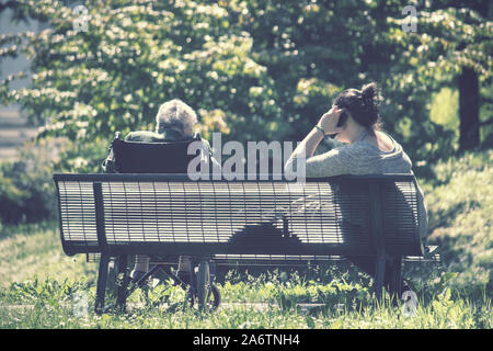 Zurück Blick auf alte Frau mit Hausmeister, Sie anruft und die Oma sitzt im Rollstuhl Stockfoto