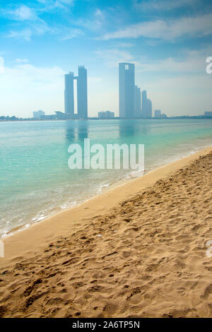 Abu Dhabi Skyline mit skyscrappers in den bachground der Ozean & einen schönen Strand im Vordergrund gegenüber, Vereinigte Arabische Emirate. Stockfoto