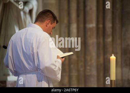 Ein römischer katholischer Priester, der eine Alb und eine Zwinkur trägt, bereitet sich auf die Sonntagsmesse in der Kathedrale von Amiens vor Stockfoto