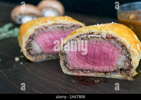 Einzelnen Beef Wellington mit Pilzsauce: Filet Mignon in Schinken gewickelt, cremini Pilz, und Blätterteig Stockfoto