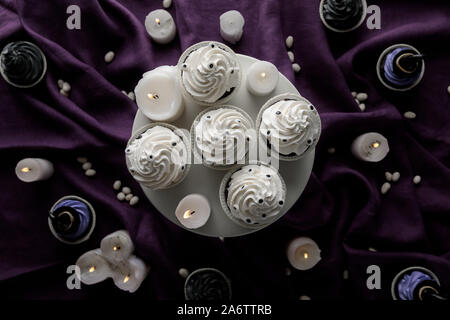 Blick von oben auf die köstliche Halloween cupcakes in der Nähe von brennenden Kerzen auf den lila Tuch Stockfoto