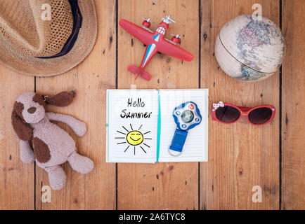 Überblick über ein Tagebuch und Reisezubehör auf alten hölzernen Tisch gelegt. Die worte Hallo Sommer lesbar sind. Travel Concept Stockfoto