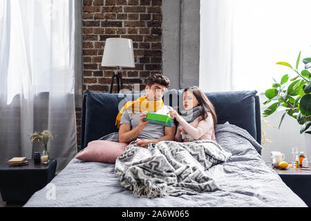 Kranken Freundin, Serviette und Freund Holding Box in der Wohnung Stockfoto