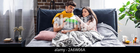 Panorama-aufnahme des kranken Freundin, Serviette und Freund Holding Box in der Wohnung Stockfoto