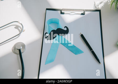 Blau awareness Ribbon, Papier schneiden Schnurrbart und Stift auf Zwischenablage mit leerem Papier in der Nähe von Stethoskop Stockfoto