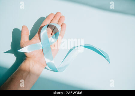 Teilweise mit Blick auf die männliche Hand mit Blau awareness Ribbon auf weißem Hintergrund Stockfoto