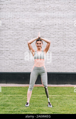 In voller Länge ansehen Der lächelnden behinderten Sportlerin Yoga auf Gras Stockfoto