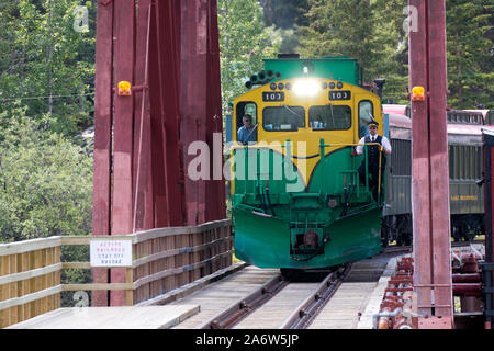 Carcross, Yukon/Kanada - 10. Juli 2019: Die White Pass und Yukon Eisenbahn überqueren der Brücke in Carcross, wie es die Station betritt. Stockfoto