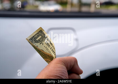 Kunden Hand schmerzhaft an halten zu einem Dollar Bill neben seinem Pick up Trucks Tankklappe. Stockfoto