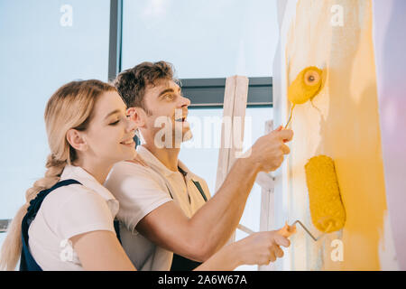 Zwei junge Maler lächelnd während Malerei Wand mit Farbe rollen Stockfoto