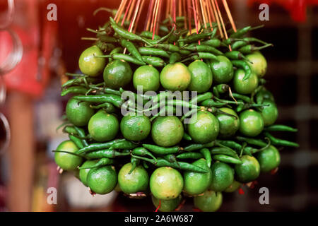 Grüne Chilischoten und Kalk. Nach indischen traditionellen Glauben eine Zeichenkette von Kalk und Chili peppers an den Eingängen als Glücksbringer aufgehängt ist. Stockfoto