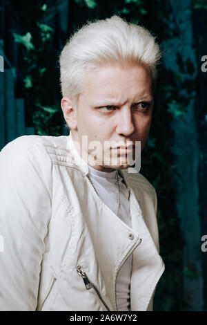 Blonder Mann tragen weiße Fashion Outfit auf dunklem Hintergrund. Stockfoto