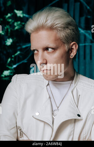 Blonder Mann tragen weiße Fashion Outfit auf dunklem Hintergrund. Stockfoto