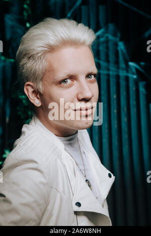 Blonder Mann tragen weiße Fashion Outfit auf dunklem Hintergrund. Stockfoto