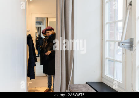 Elegante Frau mit violetten Barett innen stand Umkleidekabinen in der großen Frauen kleidung shop Messen neue warme Winter parka Stockfoto