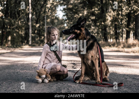 Verärgert Kind mit Teddybär berühren Deutscher Schäferhund auf der Straße, post-apokalyptischen Konzept Stockfoto