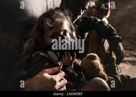 Selektiver Fokus der Mann umarmen Zicklein in der Gasmaske mit Teddybär, post-apokalyptischen Konzept Stockfoto
