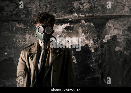 Mann in der Gasmaske in der Nähe von verwitterte Wand, post-apokalyptischen Konzept Stockfoto