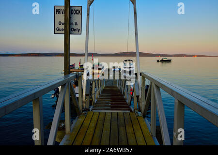 Eine Bootsanlegestelle ragt heraus in die Stewart Kanal mit Sportbooten auf einen ruhigen Sommer Abend auf Vancouver Island, British Columbia Kanada geladen. Stockfoto